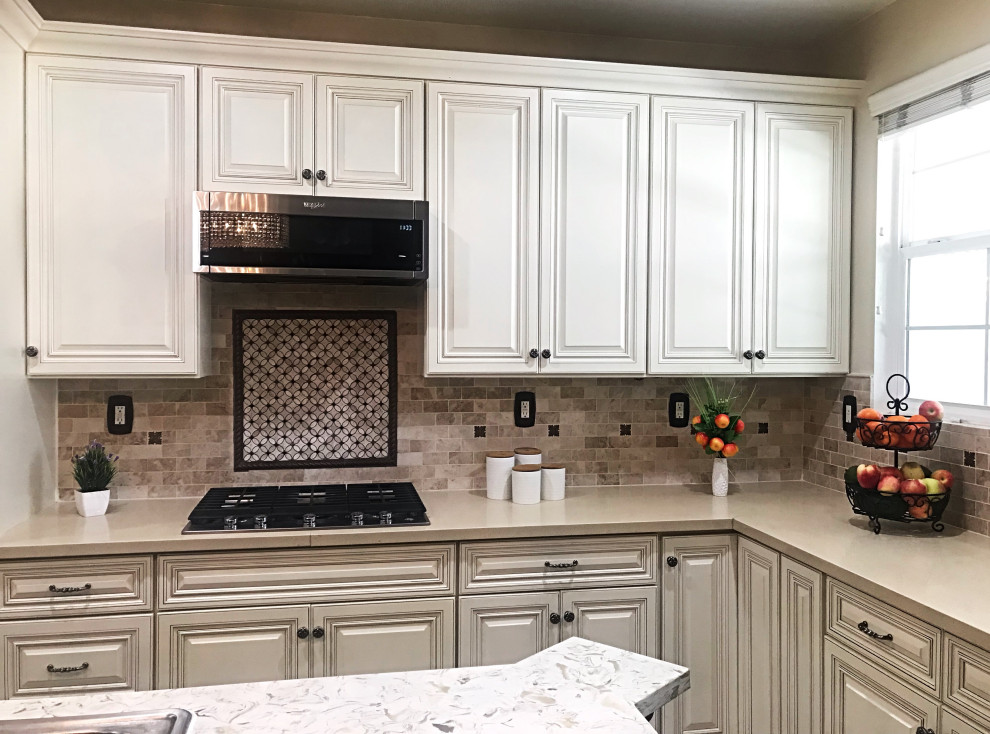 Medium sized traditional u-shaped enclosed kitchen in Orange County with a built-in sink, beaded cabinets, white cabinets, engineered stone countertops, multi-coloured splashback, porcelain splashback, stainless steel appliances, porcelain flooring, an island, beige floors and grey worktops.