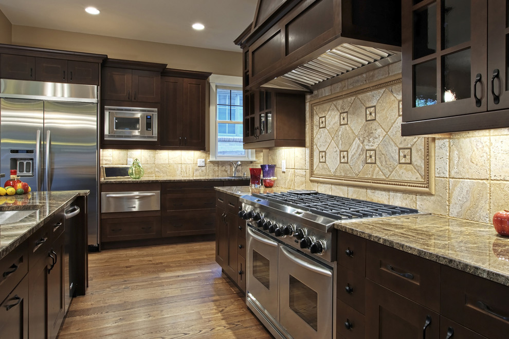 Inspiration for a large timeless u-shaped medium tone wood floor and brown floor open concept kitchen remodel in Tampa with an undermount sink, shaker cabinets, dark wood cabinets, granite countertops, beige backsplash, stainless steel appliances, an island and limestone backsplash