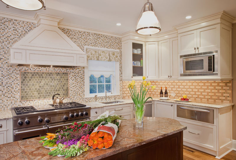 Example of a large classic single-wall medium tone wood floor enclosed kitchen design in New York with an undermount sink, recessed-panel cabinets, white cabinets, granite countertops, multicolored backsplash, mosaic tile backsplash, stainless steel appliances and an island