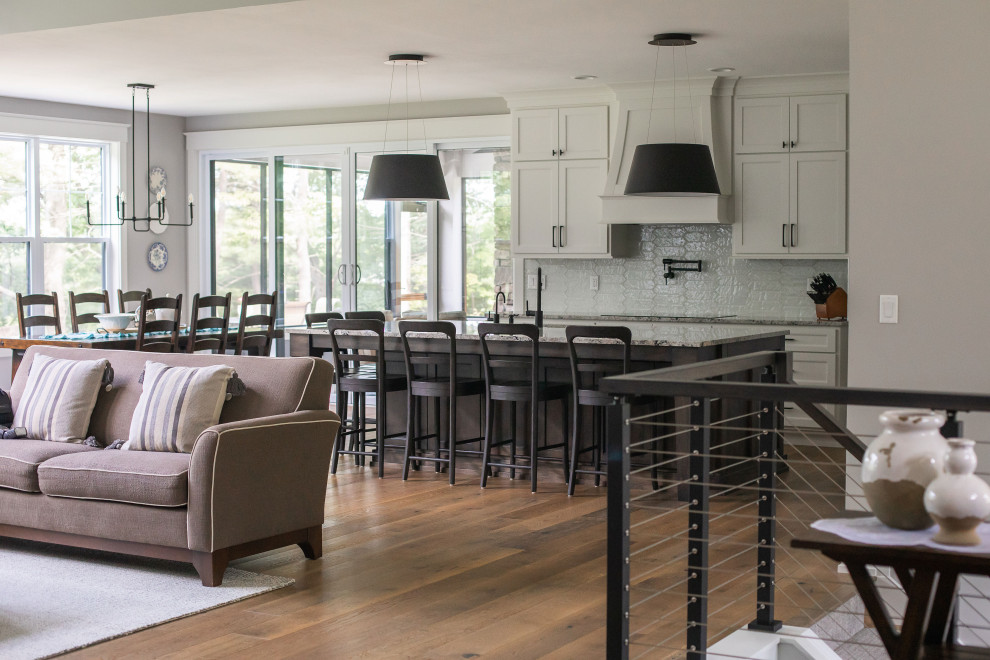 Foto på ett amerikanskt flerfärgad kök, med en undermonterad diskho, skåp i shakerstil, vita skåp, granitbänkskiva, vitt stänkskydd, stänkskydd i keramik, integrerade vitvaror, mellanmörkt trägolv, en köksö och brunt golv