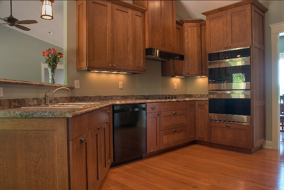 Example of a mid-sized arts and crafts u-shaped light wood floor eat-in kitchen design in Other with a double-bowl sink, recessed-panel cabinets, medium tone wood cabinets, granite countertops and stainless steel appliances