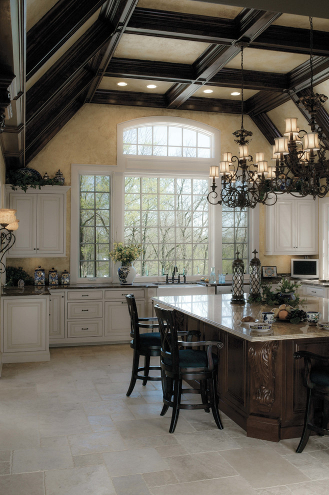 Inredning av ett rustikt mycket stort kök, med en rustik diskho, luckor med infälld panel, vita skåp, granitbänkskiva, gult stänkskydd, vita vitvaror, kalkstensgolv och en köksö