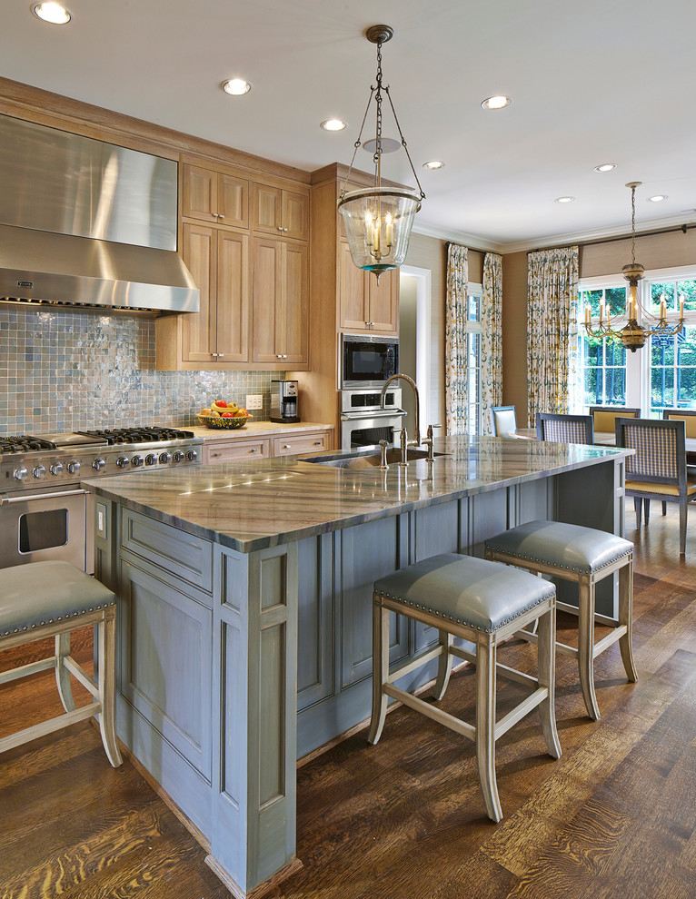Inredning av ett klassiskt stort flerfärgad flerfärgat kök, med rostfria vitvaror, en undermonterad diskho, luckor med profilerade fronter, skåp i ljust trä, bänkskiva i kvartsit, blått stänkskydd, stänkskydd i keramik, mellanmörkt trägolv, en köksö och brunt golv