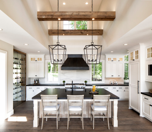 Marble Backsplash with Black Range Hood in a Farmhouse White Kitchen Cabinets with Black Countertop