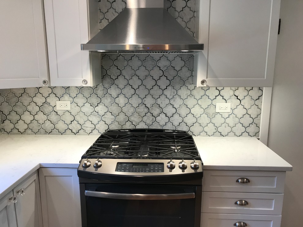 Photo of a medium sized classic u-shaped kitchen/diner in Chicago with a built-in sink, recessed-panel cabinets, white cabinets, engineered stone countertops, grey splashback, mosaic tiled splashback, stainless steel appliances, light hardwood flooring, a breakfast bar and orange floors.