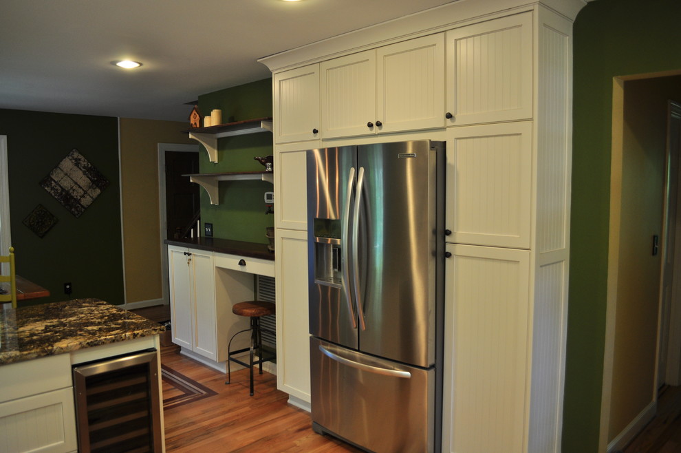 Foto på ett mellanstort lantligt kök, med luckor med infälld panel, vita skåp, granitbänkskiva, rostfria vitvaror och en halv köksö