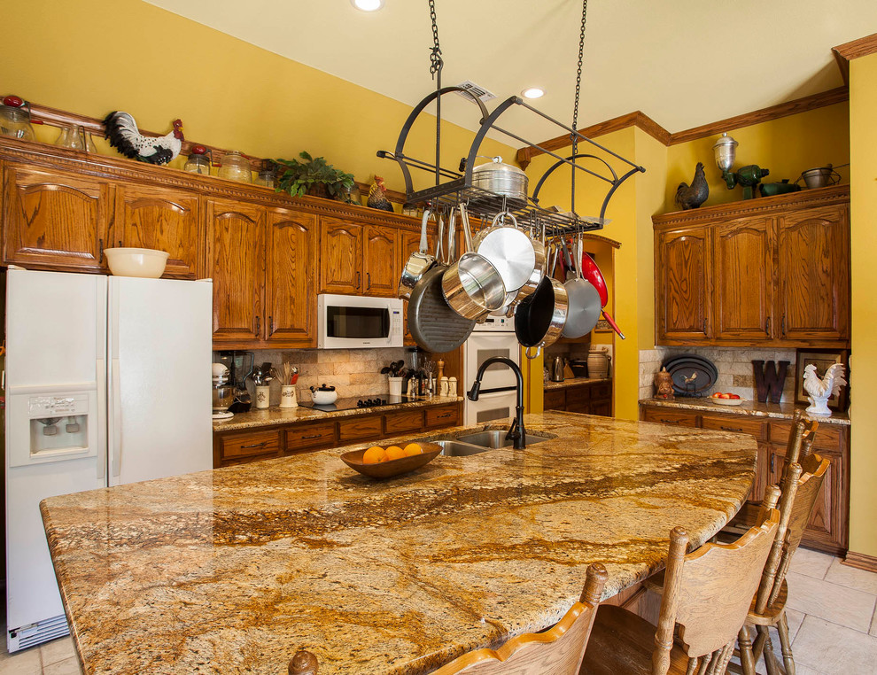 Klassische Küche in L-Form mit Doppelwaschbecken, profilierten Schrankfronten, hellbraunen Holzschränken, Küchenrückwand in Beige und weißen Elektrogeräten in Dallas