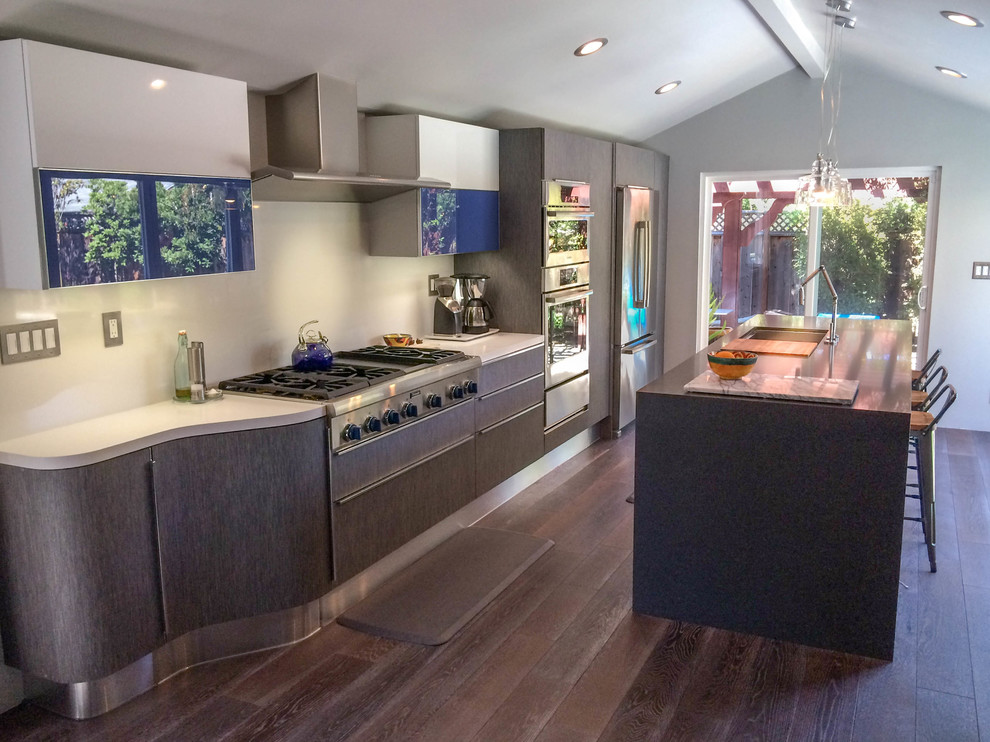 Foto på ett mellanstort funkis linjärt kök med öppen planlösning, med en enkel diskho, släta luckor, grå skåp, bänkskiva i kvarts, vitt stänkskydd, stänkskydd i sten, rostfria vitvaror, mörkt trägolv och en köksö