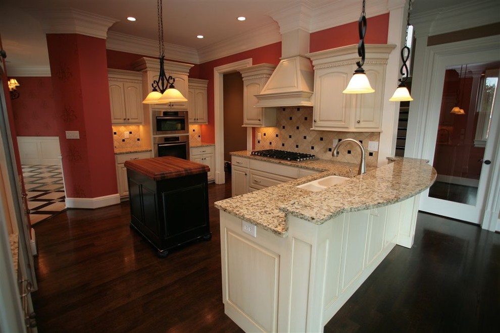Photo of a large classic u-shaped kitchen in Louisville with a double-bowl sink, raised-panel cabinets, white cabinets, granite worktops, beige splashback, stone tiled splashback, stainless steel appliances, dark hardwood flooring, an island and brown floors.