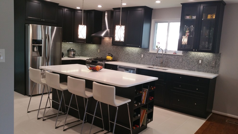 Photo of a large contemporary l-shaped enclosed kitchen in DC Metro with a submerged sink, shaker cabinets, dark wood cabinets, engineered stone countertops, black splashback, mosaic tiled splashback, stainless steel appliances, ceramic flooring, an island and beige floors.
