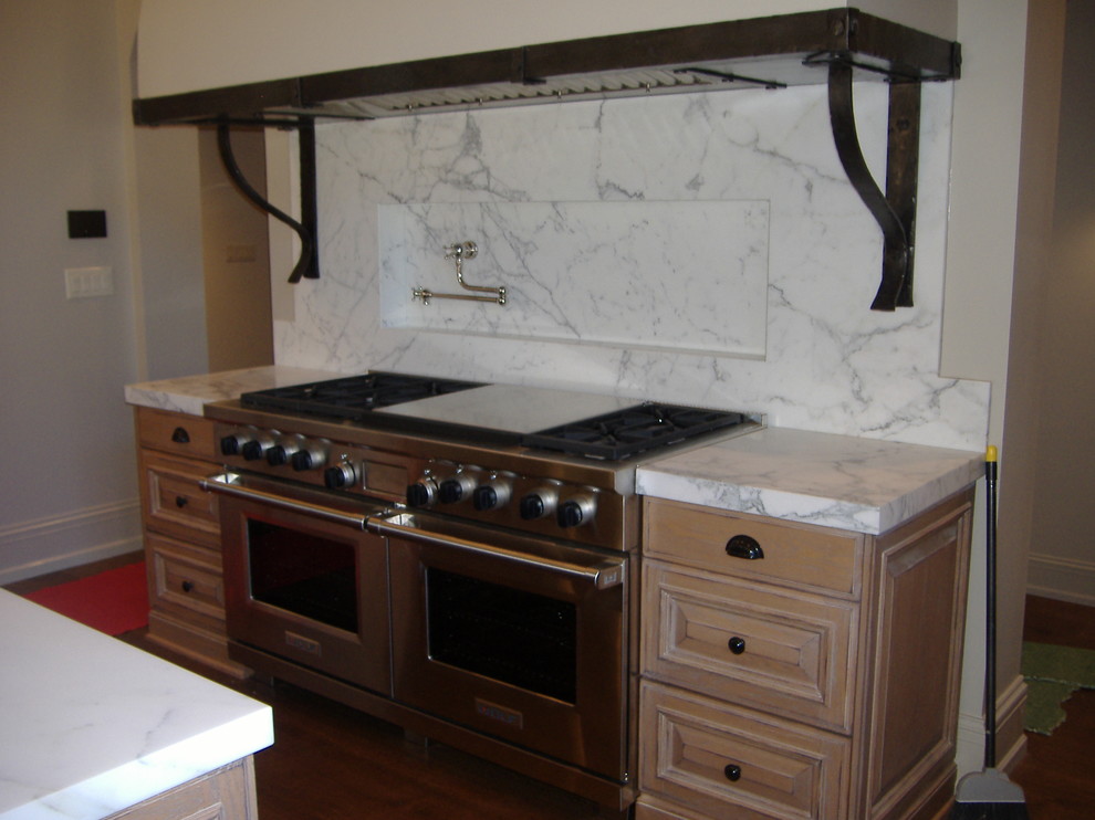 Example of a classic u-shaped eat-in kitchen design in Indianapolis with a farmhouse sink, raised-panel cabinets, light wood cabinets, marble countertops and stainless steel appliances