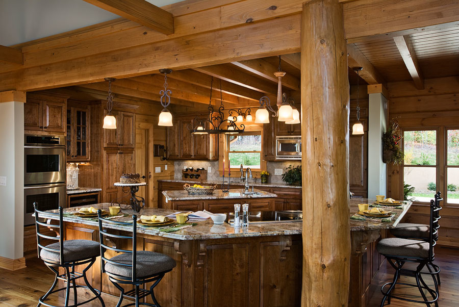 Example of a mid-sized mountain style l-shaped medium tone wood floor and brown floor open concept kitchen design in Other with an undermount sink, raised-panel cabinets, dark wood cabinets, granite countertops, beige backsplash, stone tile backsplash, stainless steel appliances and an island
