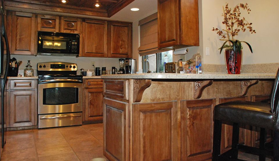 Klassisk inredning av ett stort kök, med en nedsänkt diskho, skåp i mörkt trä, granitbänkskiva, flerfärgad stänkskydd, rostfria vitvaror, klinkergolv i keramik, luckor med upphöjd panel och beiget golv