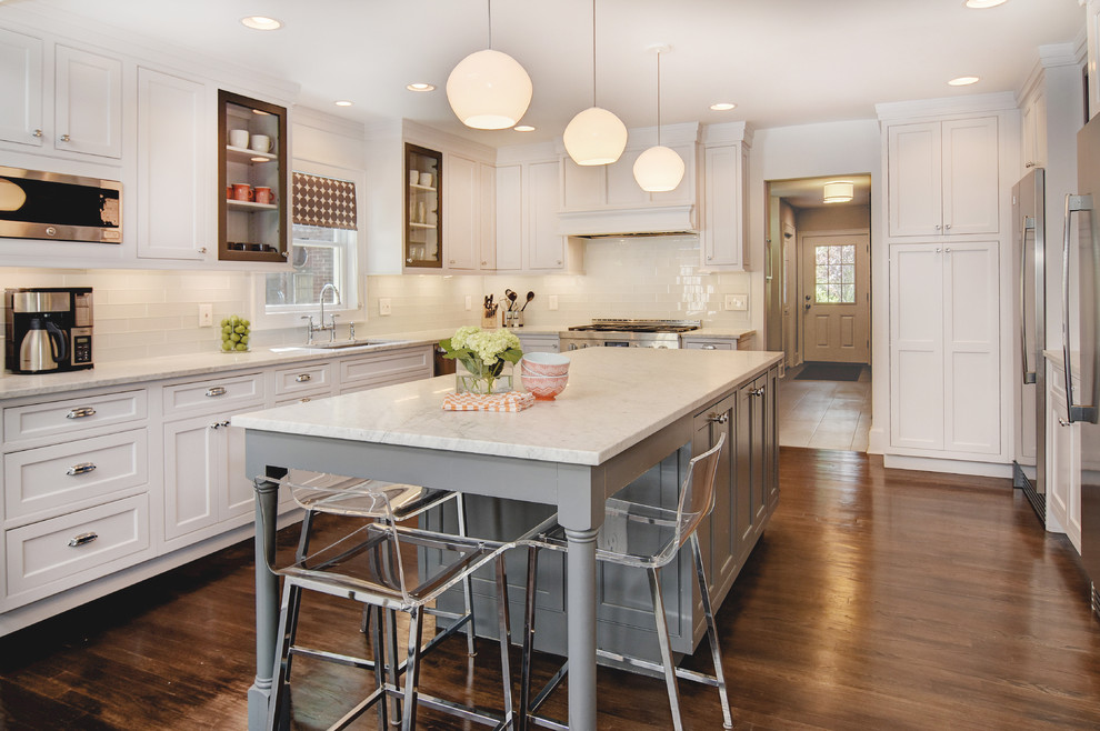 Inspiration for a mid-sized transitional u-shaped dark wood floor open concept kitchen remodel in Newark with an undermount sink, beaded inset cabinets, white cabinets, marble countertops, white backsplash, glass tile backsplash, stainless steel appliances and an island