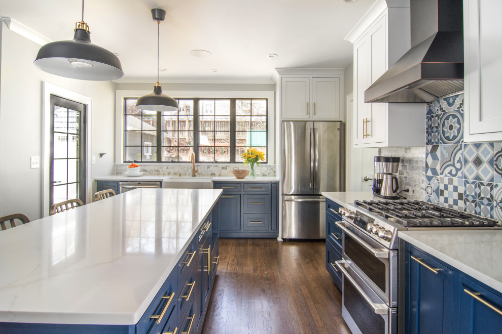 Eat-in kitchen - mid-sized industrial l-shaped dark wood floor and brown floor eat-in kitchen idea in Newark with a farmhouse sink, shaker cabinets, blue cabinets, quartz countertops, blue backsplash, porcelain backsplash, stainless steel appliances, an island and gray countertops