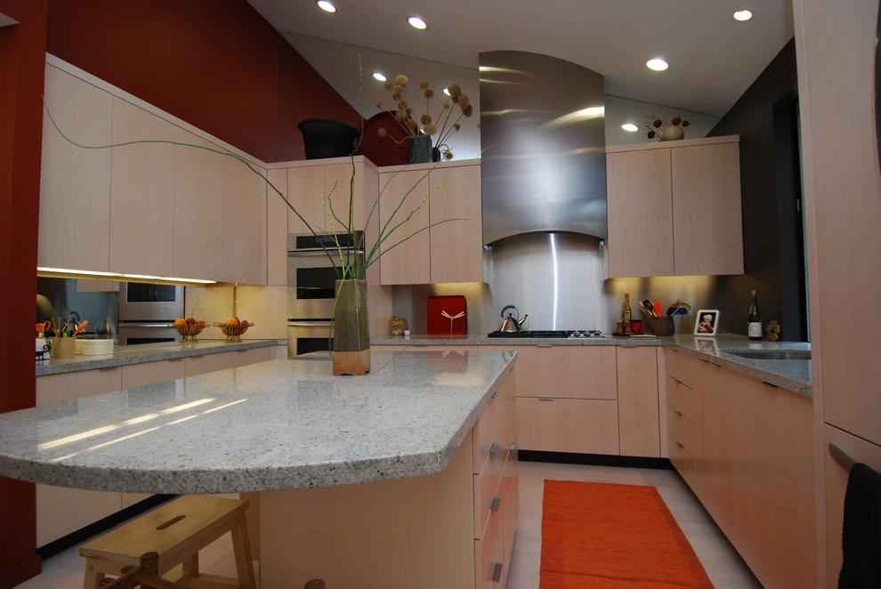 Cette image montre une cuisine design en U et bois clair fermée avec un placard à porte plane, une crédence métallisée et une crédence miroir.