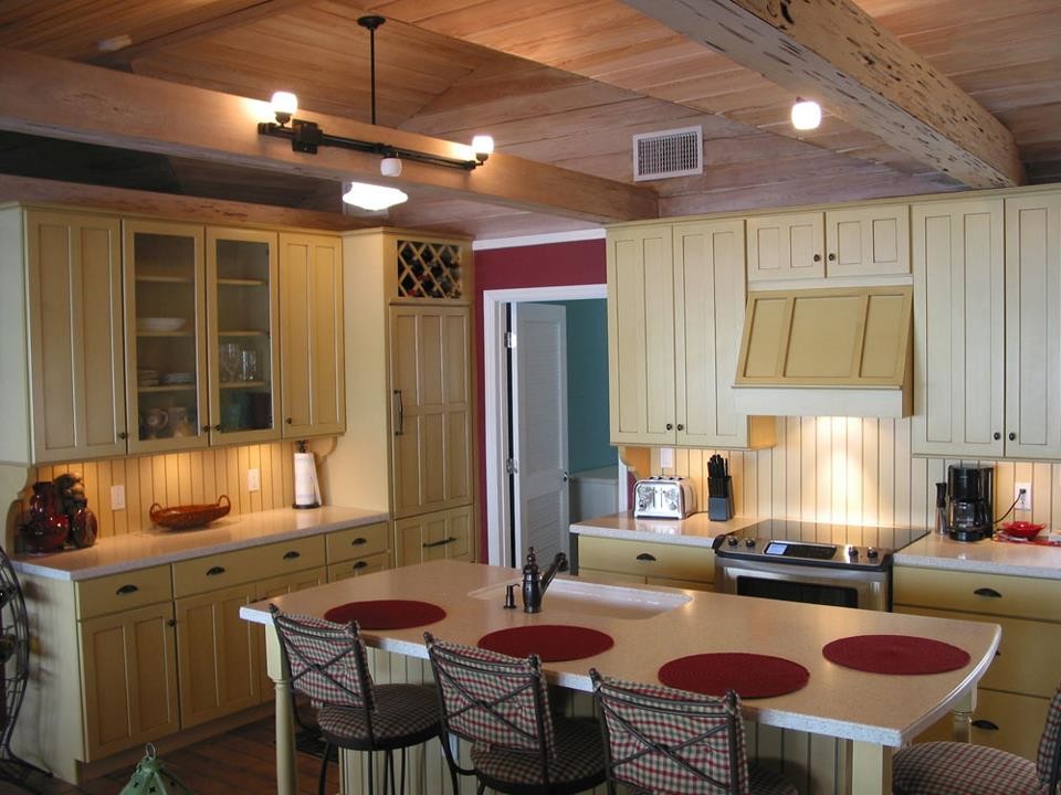 Idéer för mellanstora vintage flerfärgat kök, med en undermonterad diskho, skåp i shakerstil, en köksö, brunt golv, gula skåp, bänkskiva i terrazo, gult stänkskydd, stänkskydd i trä, integrerade vitvaror och mellanmörkt trägolv