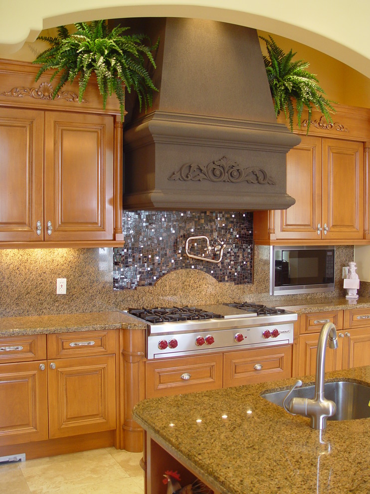 Immagine di una cucina mediterranea con top in granito, lavello sottopiano, ante con bugna sagomata, ante in legno scuro e elettrodomestici in acciaio inossidabile