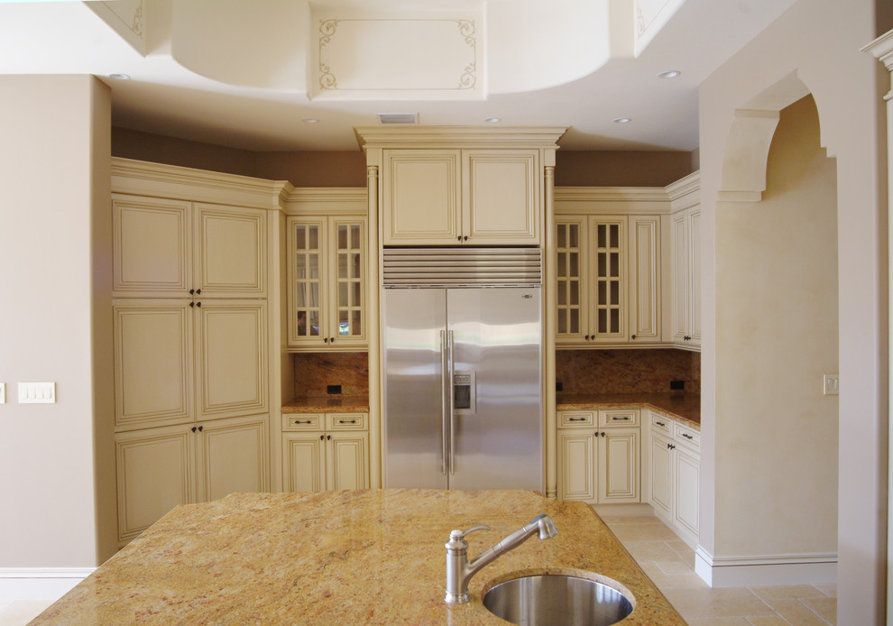 Cette image montre une cuisine méditerranéenne avec un évier encastré, un placard avec porte à panneau surélevé, des portes de placard beiges et un électroménager en acier inoxydable.