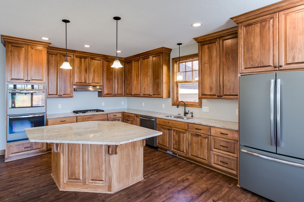 Medium sized classic l-shaped kitchen/diner in Minneapolis with a double-bowl sink, raised-panel cabinets, composite countertops, white splashback, stainless steel appliances, an island and dark hardwood flooring.