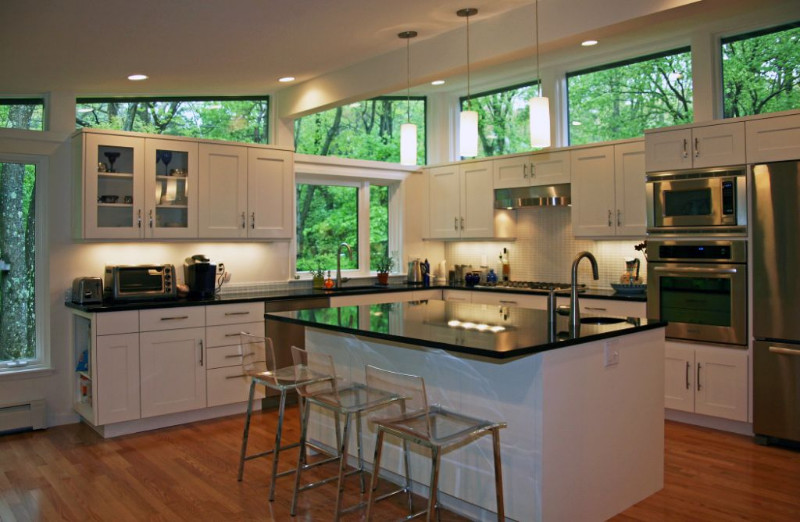 Inspiration for a large transitional l-shaped medium tone wood floor eat-in kitchen remodel in Boston with a single-bowl sink, shaker cabinets, white cabinets, granite countertops, white backsplash, mosaic tile backsplash, stainless steel appliances and an island