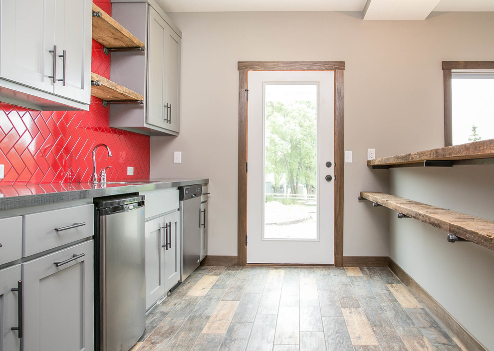 Modelo de cocina campestre con armarios estilo shaker, puertas de armario grises, salpicadero rojo, suelo de madera en tonos medios, península y barras de cocina