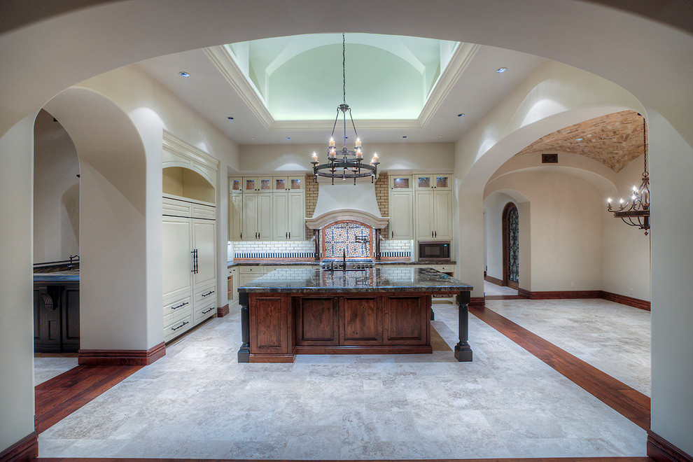 Example of a huge transitional u-shaped medium tone wood floor enclosed kitchen design in Phoenix with a farmhouse sink, granite countertops, stainless steel appliances, glass-front cabinets, medium tone wood cabinets, beige backsplash, mosaic tile backsplash and two islands