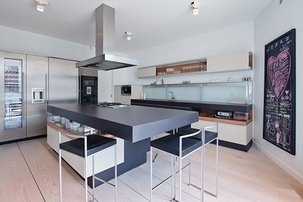 Immagine di un cucina con isola centrale moderno con nessun'anta, ante beige, top in laminato, elettrodomestici neri e parquet chiaro