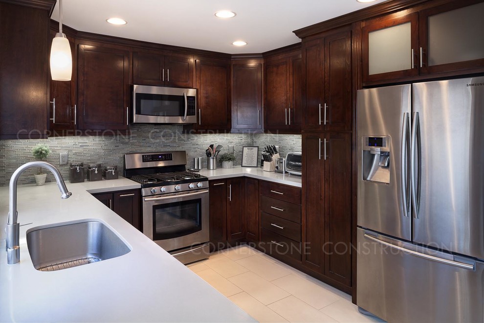 Example of a mid-sized trendy galley porcelain tile enclosed kitchen design in Los Angeles with multicolored backsplash, glass tile backsplash, stainless steel appliances, an undermount sink, shaker cabinets, dark wood cabinets and quartzite countertops