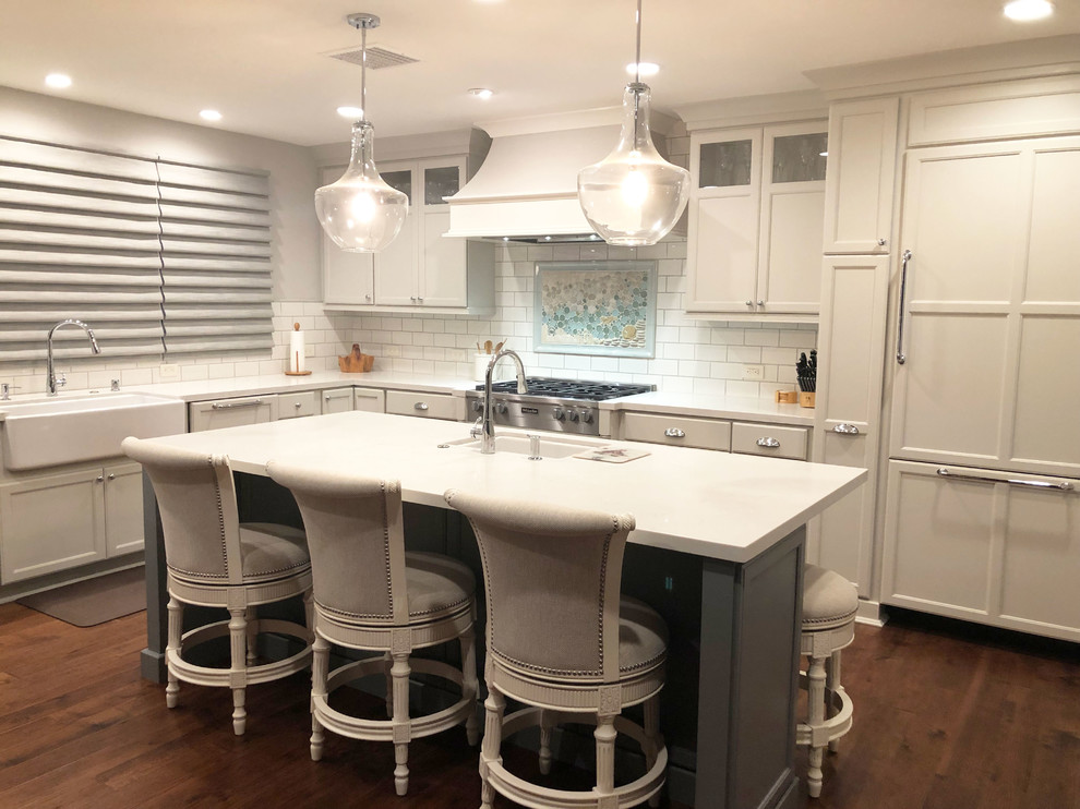 Modern inredning av ett stort vit vitt kök, med en rustik diskho, luckor med infälld panel, vita skåp, flerfärgad stänkskydd, stänkskydd i mosaik, rostfria vitvaror och en köksö