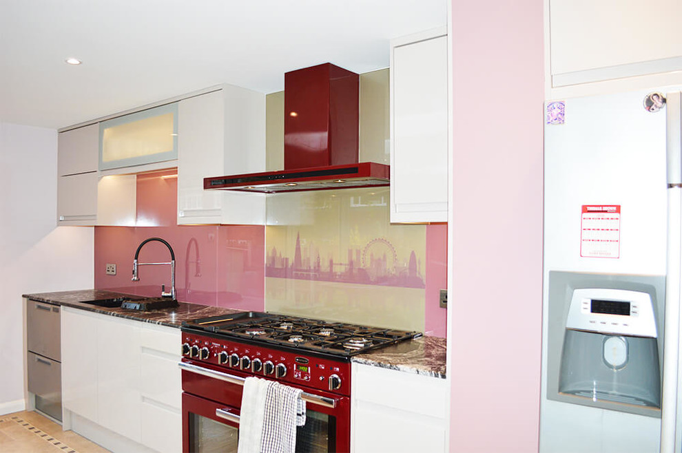 Cette photo montre une grande cuisine américaine moderne avec un placard à porte plane, des portes de placard blanches, plan de travail en marbre, une crédence rose, une crédence en feuille de verre et îlot.