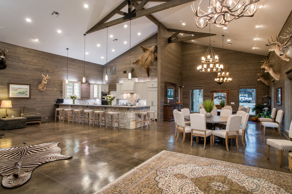 Photo of a large rustic u-shaped open plan kitchen in Austin with concrete flooring, a submerged sink, beaded cabinets, grey cabinets, engineered stone countertops, grey splashback, stone tiled splashback, stainless steel appliances, a breakfast bar, brown floors and grey worktops.