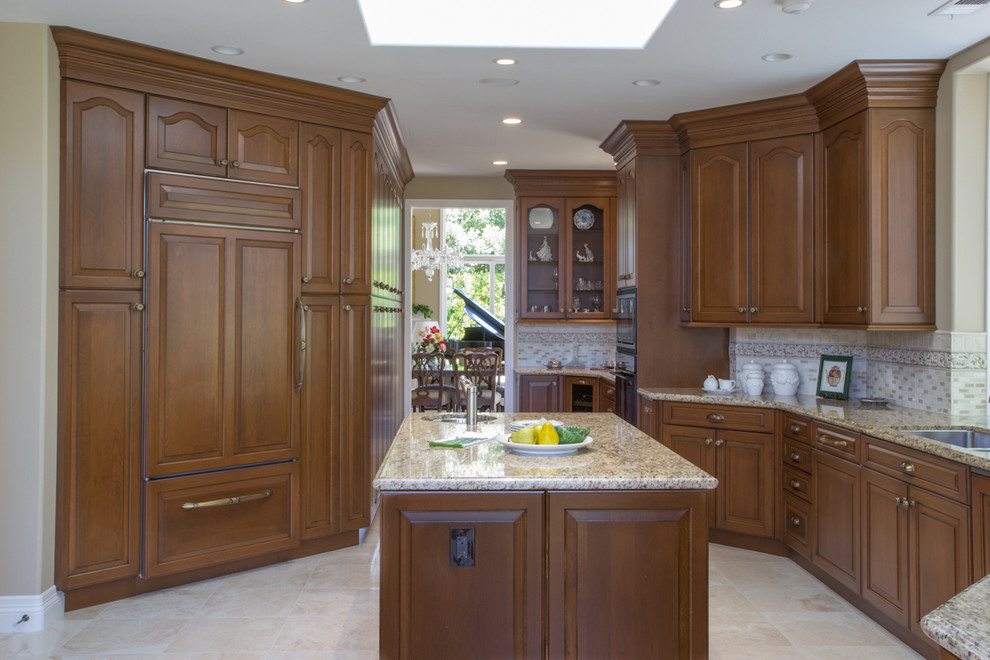 Inspiration for a timeless u-shaped eat-in kitchen remodel in San Diego with an undermount sink, raised-panel cabinets, medium tone wood cabinets, granite countertops, beige backsplash, ceramic backsplash and paneled appliances