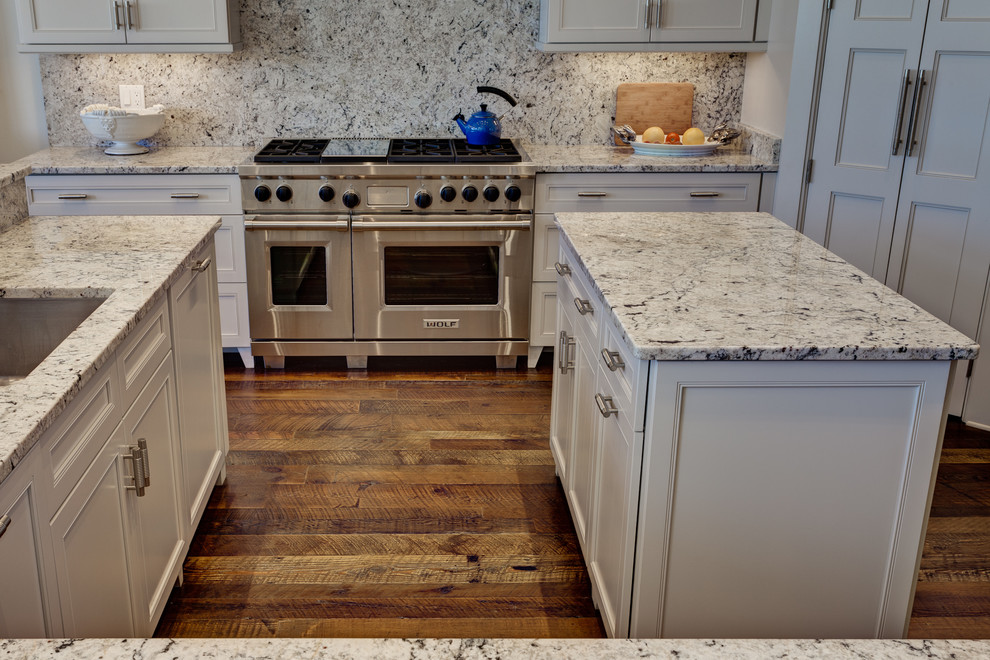 Example of a large beach style u-shaped dark wood floor eat-in kitchen design in Miami with an undermount sink, recessed-panel cabinets, white cabinets, granite countertops, stone slab backsplash, stainless steel appliances and an island
