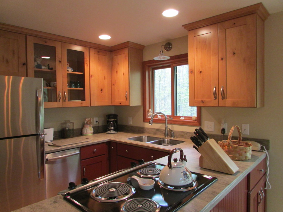 This is an example of a rustic u-shaped kitchen in Other with a submerged sink, shaker cabinets, red cabinets, composite countertops, stainless steel appliances, light hardwood flooring, a breakfast bar and beige worktops.
