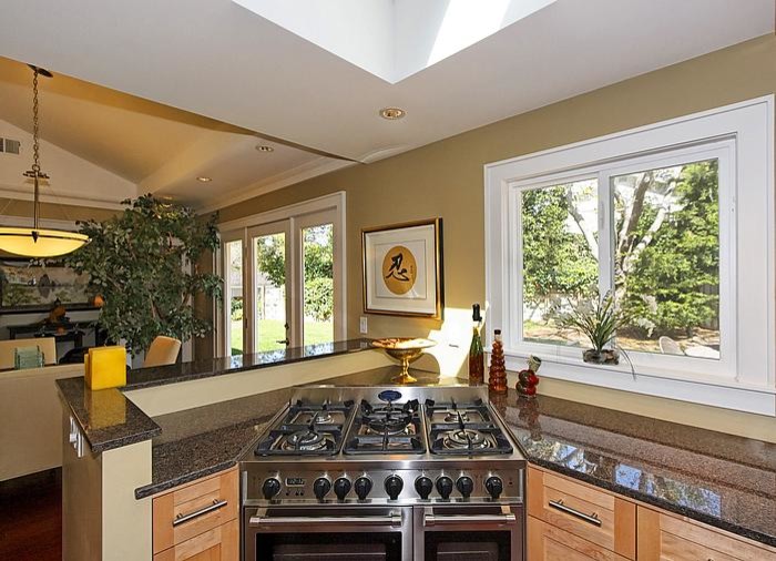 Foto på ett mellanstort flerfärgad kök, med en undermonterad diskho, skåp i shakerstil, skåp i ljust trä, granitbänkskiva, rostfria vitvaror, mörkt trägolv och en halv köksö