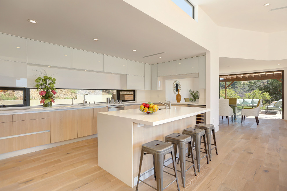 Ispirazione per una cucina contemporanea con ante lisce, ante in legno chiaro, pavimento in legno massello medio, pavimento marrone e top bianco