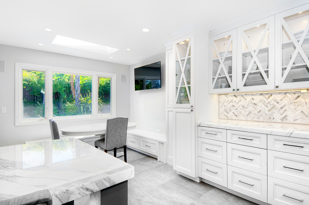 Example of a large transitional u-shaped cement tile floor eat-in kitchen design in San Francisco with a farmhouse sink, recessed-panel cabinets, white cabinets, marble countertops, white backsplash, stone tile backsplash, stainless steel appliances and an island