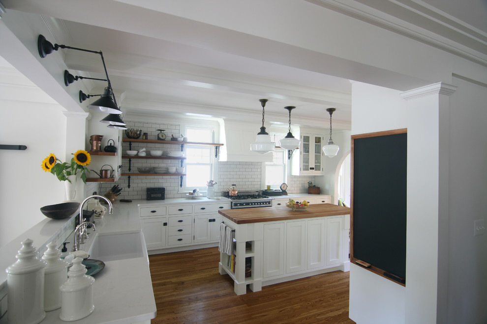 Inspiration för ett mellanstort, avskilt lantligt vit vitt l-kök, med en rustik diskho, skåp i shakerstil, vita skåp, vitt stänkskydd, stänkskydd i tunnelbanekakel, mellanmörkt trägolv, en köksö, brunt golv, marmorbänkskiva och integrerade vitvaror