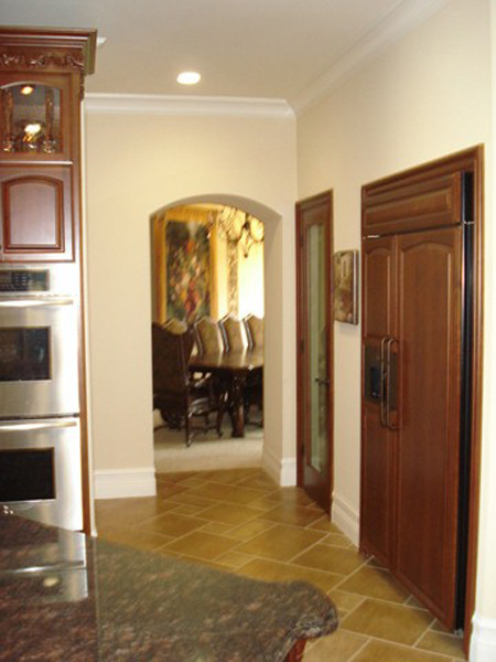 Inspiration for a mid-sized timeless galley ceramic tile, black floor and coffered ceiling open concept kitchen remodel in Los Angeles with an undermount sink, raised-panel cabinets, dark wood cabinets, granite countertops, multicolored backsplash, stone tile backsplash, stainless steel appliances and an island
