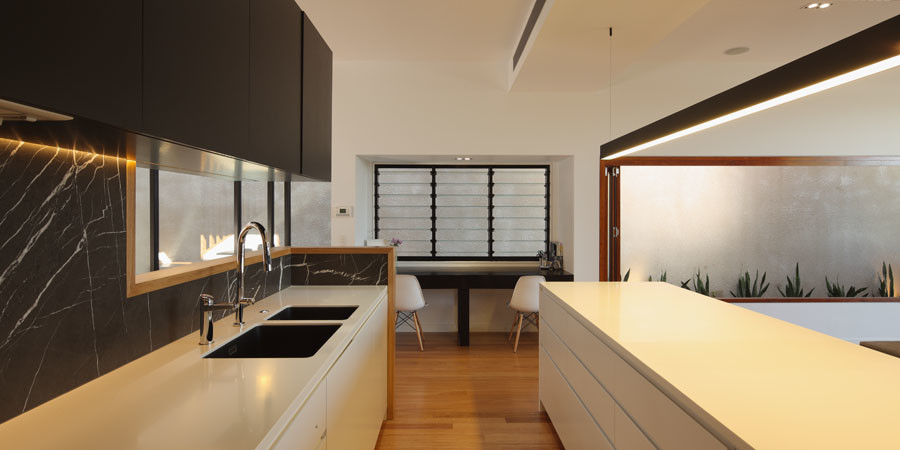Exempel på ett modernt kök, med en undermonterad diskho, vita skåp, marmorbänkskiva, svart stänkskydd, stänkskydd i marmor, rostfria vitvaror, mellanmörkt trägolv och en köksö