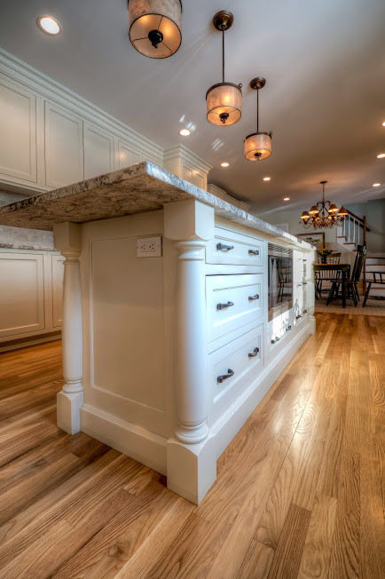 Large elegant u-shaped light wood floor and brown floor eat-in kitchen photo in Boston with an undermount sink, beaded inset cabinets, white cabinets, granite countertops, beige backsplash, stainless steel appliances, an island and stone tile backsplash