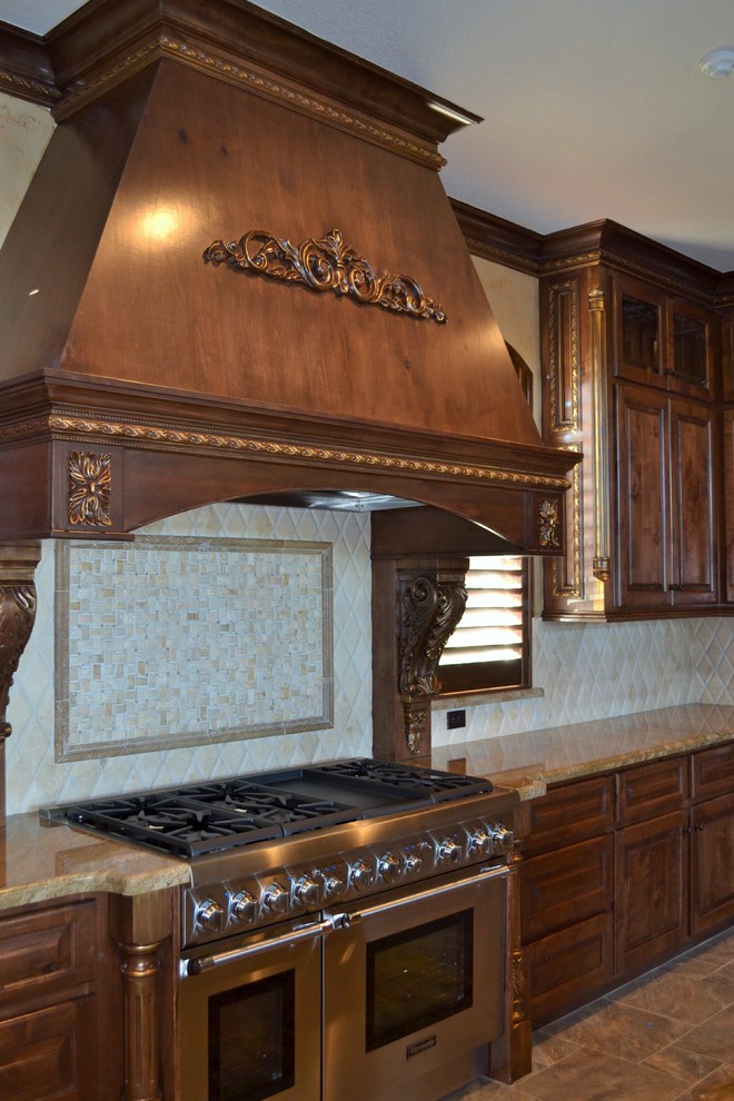 Exempel på ett stort klassiskt kök, med en undermonterad diskho, luckor med upphöjd panel, skåp i mörkt trä, granitbänkskiva, beige stänkskydd, stänkskydd i stenkakel, rostfria vitvaror, travertin golv och en köksö