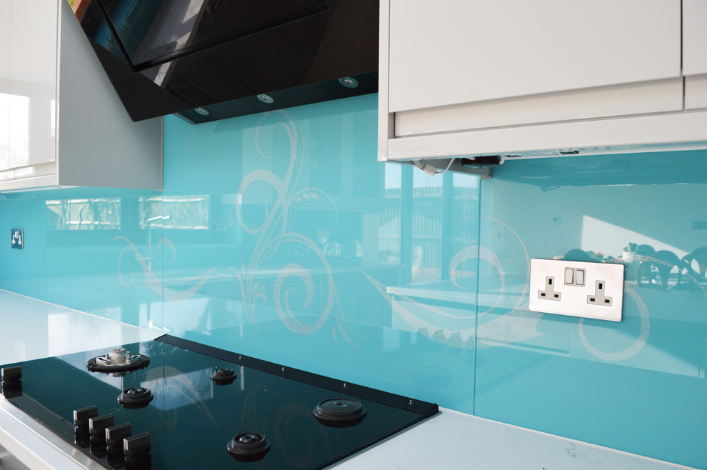 Inspiration for a large modern kitchen/diner in Hertfordshire with flat-panel cabinets, white cabinets, marble worktops, blue splashback, glass sheet splashback and an island.
