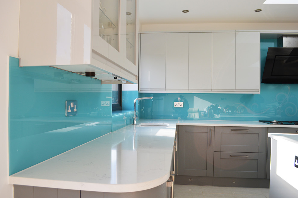 Bild på ett stort funkis kök och matrum, med släta luckor, vita skåp, marmorbänkskiva, blått stänkskydd, glaspanel som stänkskydd och en köksö