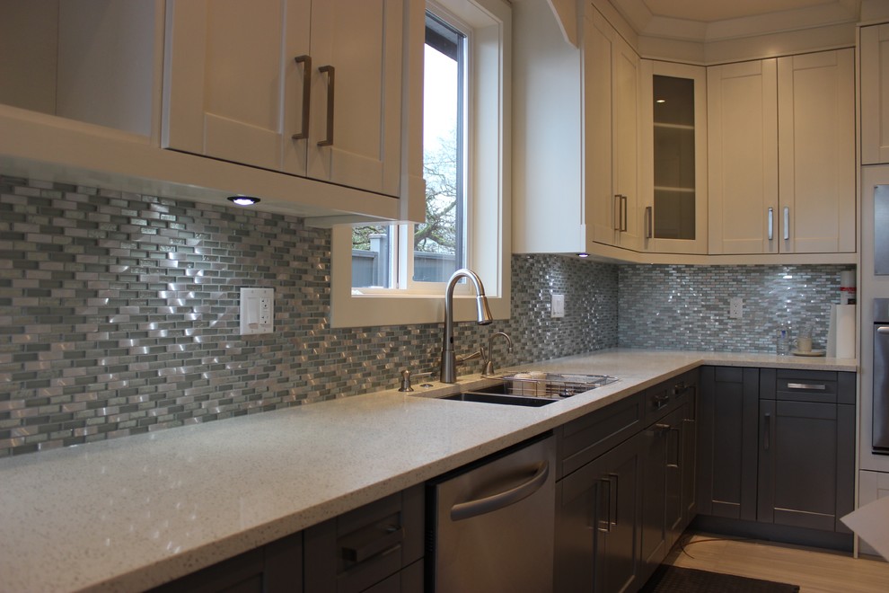 Bild på ett stort funkis kök, med luckor med infälld panel, vita skåp, stänkskydd med metallisk yta, stänkskydd i stickkakel, rostfria vitvaror, en köksö, en dubbel diskho, granitbänkskiva och ljust trägolv