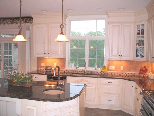 Inredning av ett klassiskt kök, med en enkel diskho, luckor med upphöjd panel, vita skåp, granitbänkskiva, flerfärgad stänkskydd, stänkskydd i keramik, rostfria vitvaror, klinkergolv i keramik och en köksö