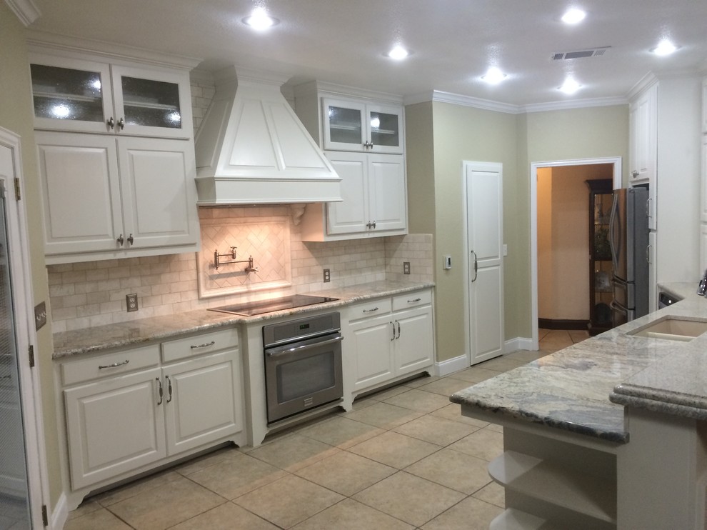 Example of a large transitional u-shaped porcelain tile eat-in kitchen design in Dallas with an undermount sink, raised-panel cabinets, white cabinets, granite countertops, beige backsplash, subway tile backsplash, stainless steel appliances and an island
