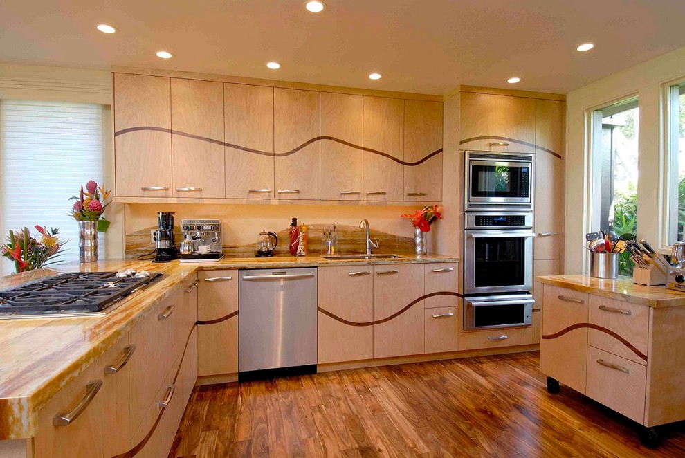 Bild på ett tropiskt kök, med en undermonterad diskho, släta luckor, skåp i ljust trä, bänkskiva i kvartsit, orange stänkskydd, stänkskydd i sten, rostfria vitvaror, mellanmörkt trägolv och en köksö
