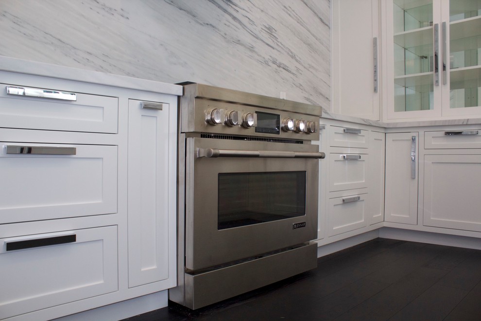 Modern inredning av ett avskilt u-kök, med en undermonterad diskho, skåp i shakerstil, vita skåp, marmorbänkskiva, grått stänkskydd, stänkskydd i marmor, rostfria vitvaror, mörkt trägolv och svart golv